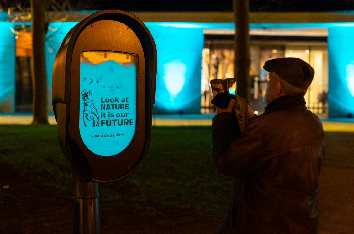 Urban signage done with bioluminescent liquid, with the words : Look at Nature, it is our future, by Leonardo da vinci